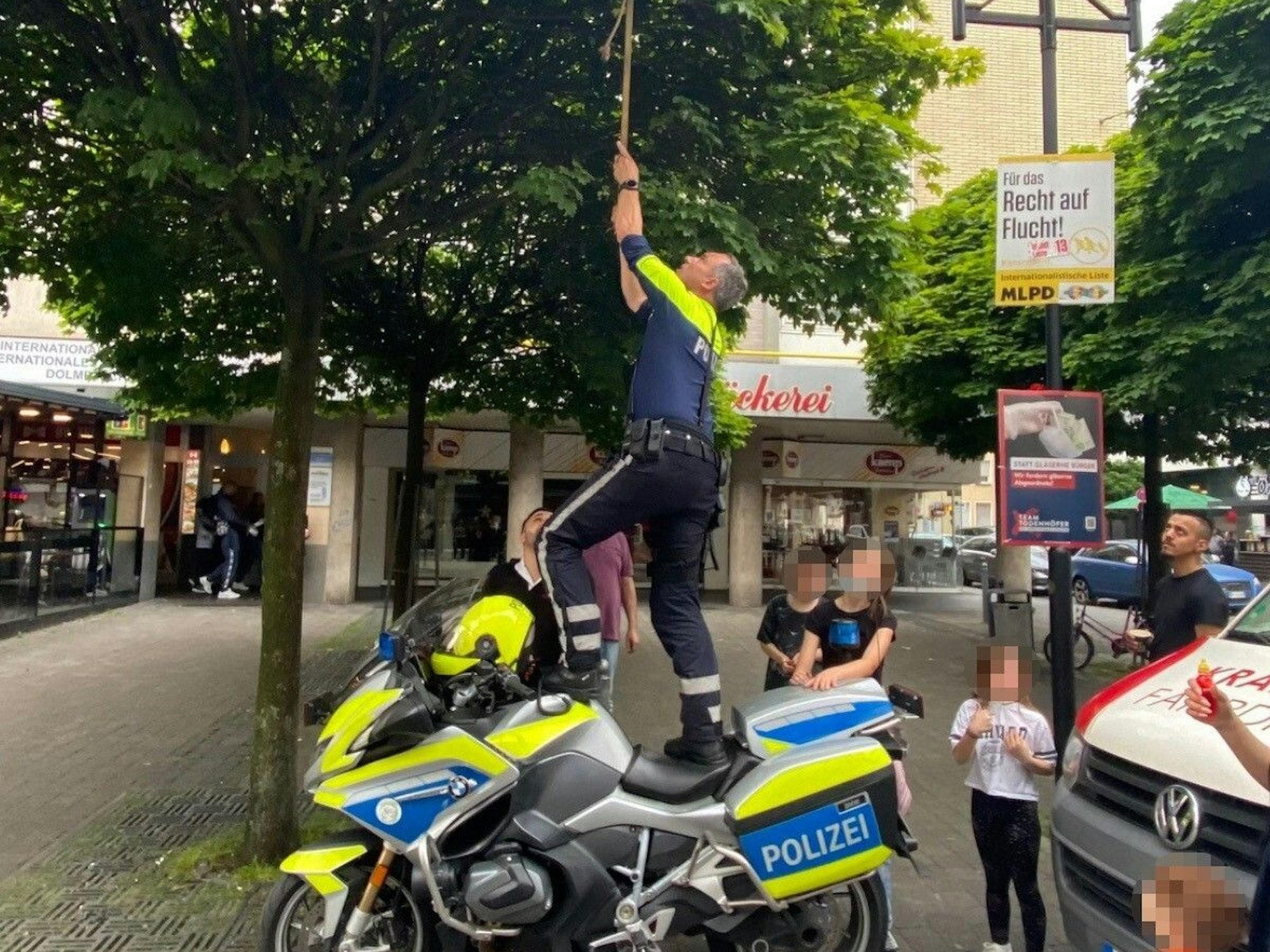 Ein Motorradpolizist aus Hagen steht auf seinem Motorrad, um einen Ball aus einem Baum zu holen.