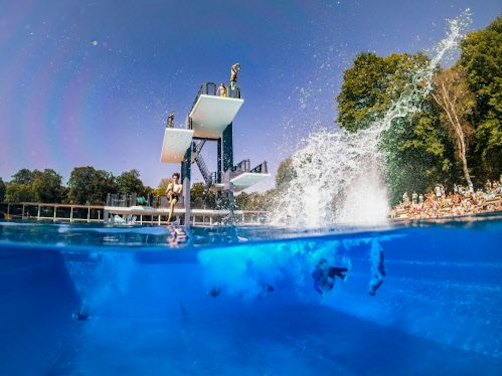 Turmspringer der Showdiving-Gruppe 'Cologne Bombs' springen am Sonntag (1. Juli 2018) im Freibad Stadionbad in Köln ins Wasser.