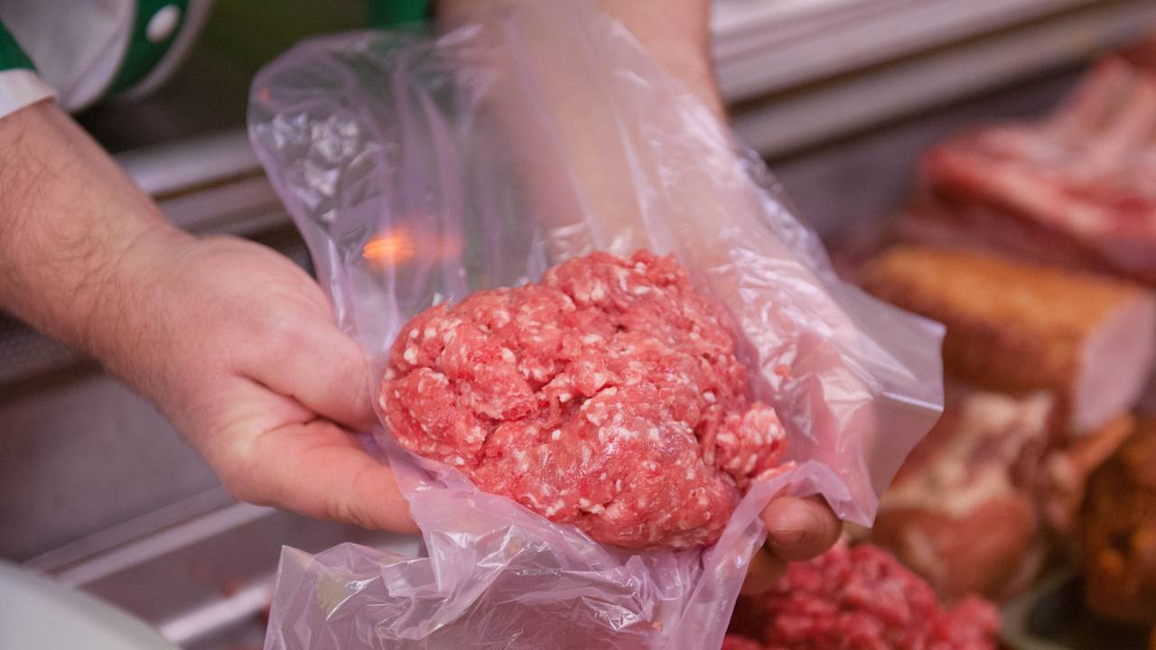 Ein Mitarbeiter eines Fleischerei-Fachgeschäfts hält eine Portion Mett in der Hand.
