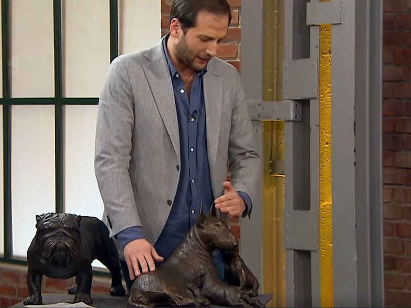 Händler Julian begutachtet zwei Hunde-Skulpturen.