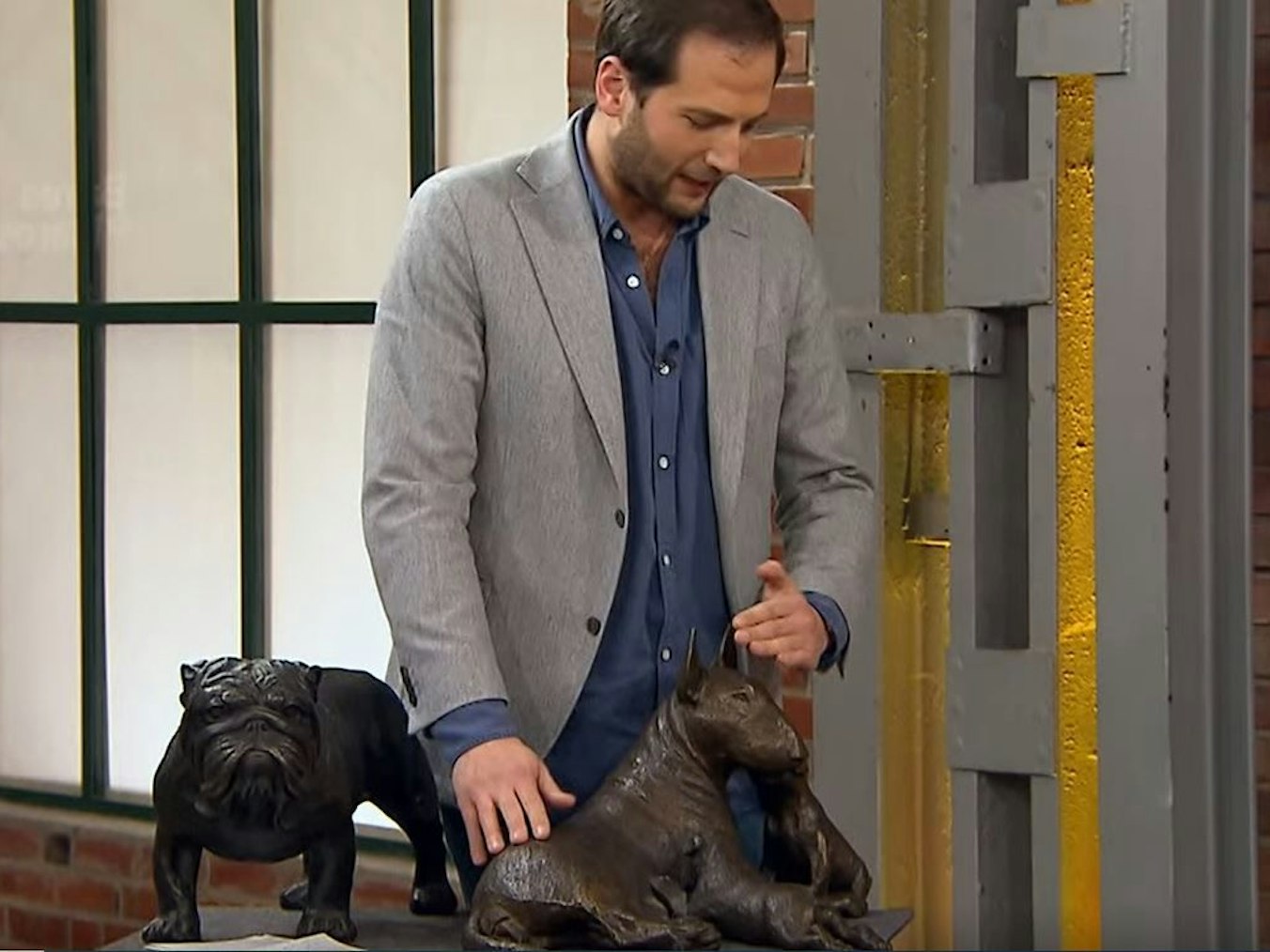 Händler Julian begutachtet zwei Hunde-Skulpturen.