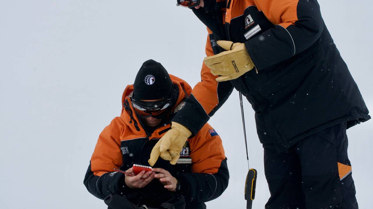 Die Studentin Alex Aves (l.) notiert Daten während der Probennahme von Schnee in der Antarktis. Sie hat im frisch gefallen Schnee einen schockierenden Fund gemacht.