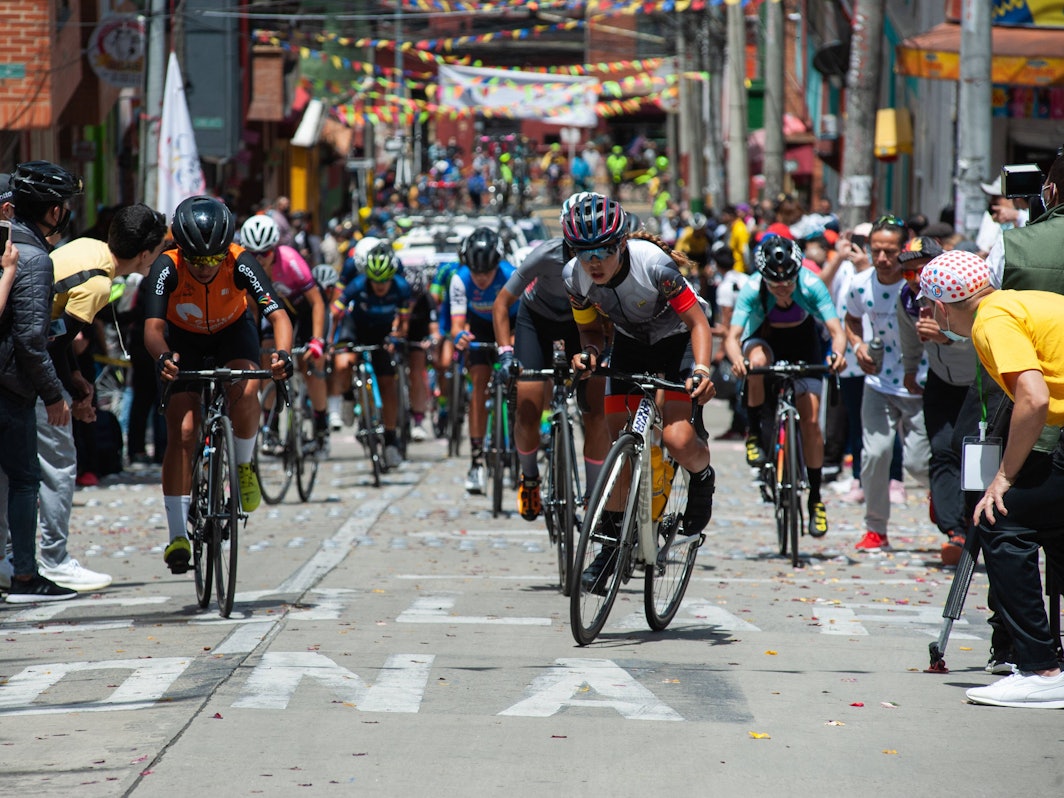 Die Rad-Profis kämpfen sich bei der Vuelta a Colombia auf einer schmalen Gasse den Berg hoch – Fans feuern von allen Seiten an.