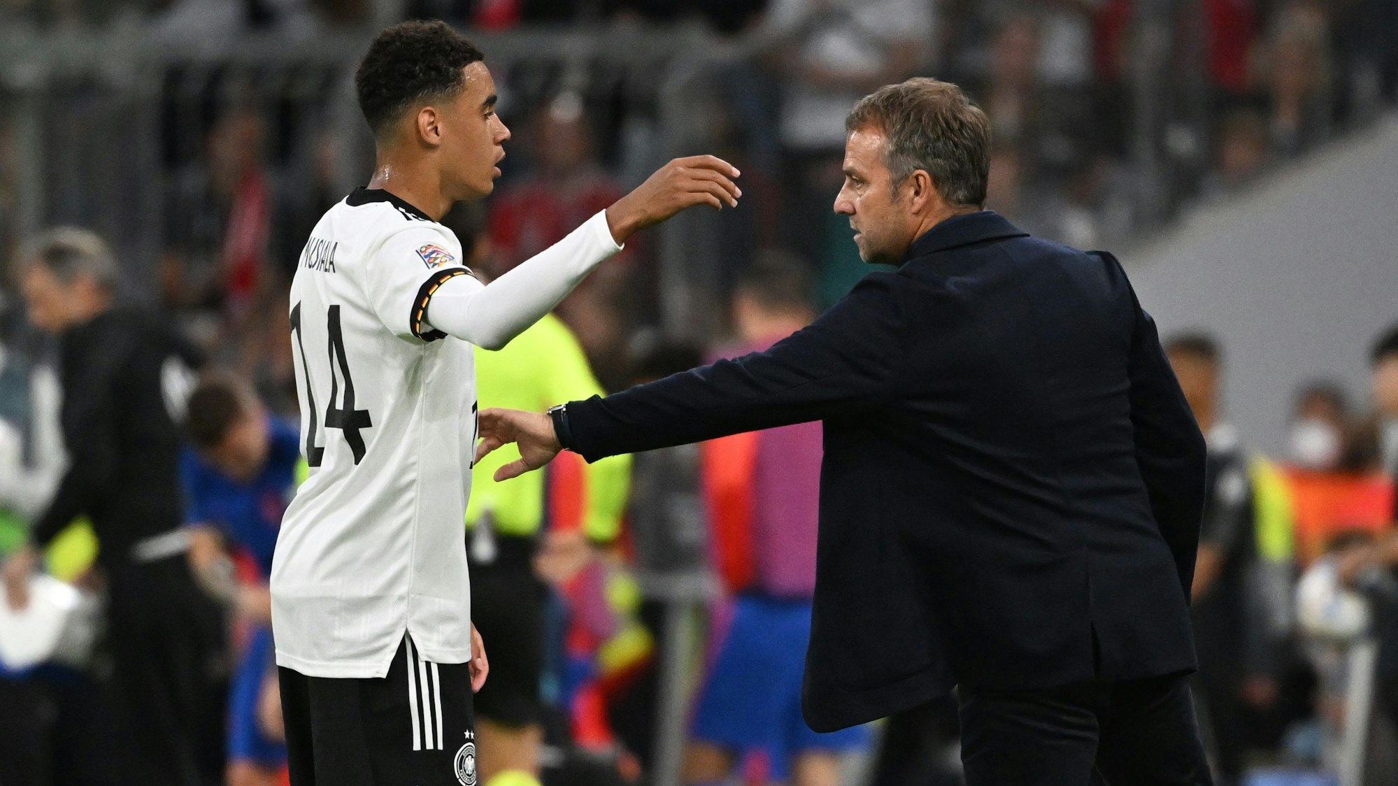 Bundestrainer Hansi Flick und Jamal Musiala unterhalten sich während des Spiels.