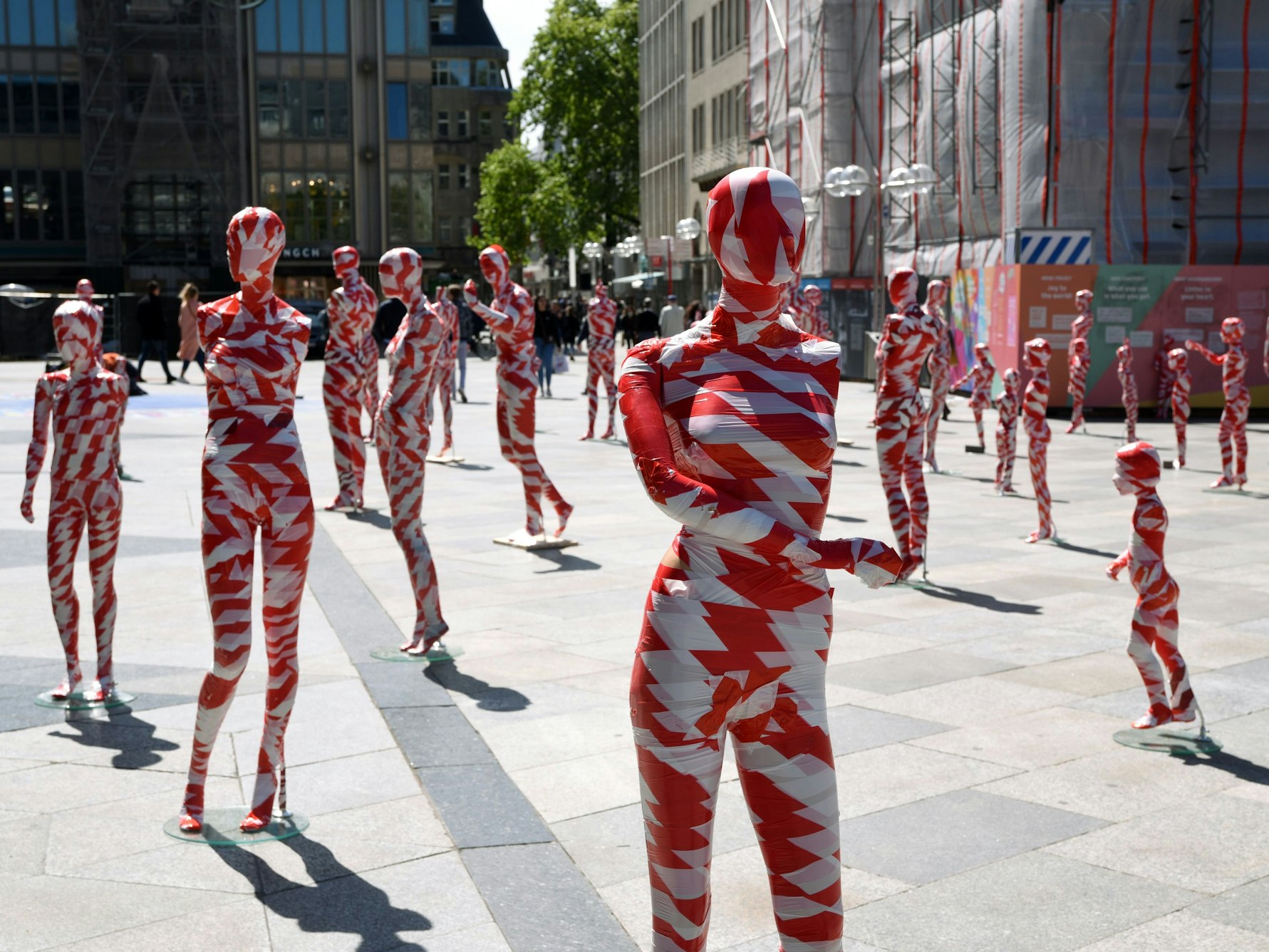 In rot-weißem Absperrband eingewickelte Schaufensterpuppen stehen auf der Domplatte.