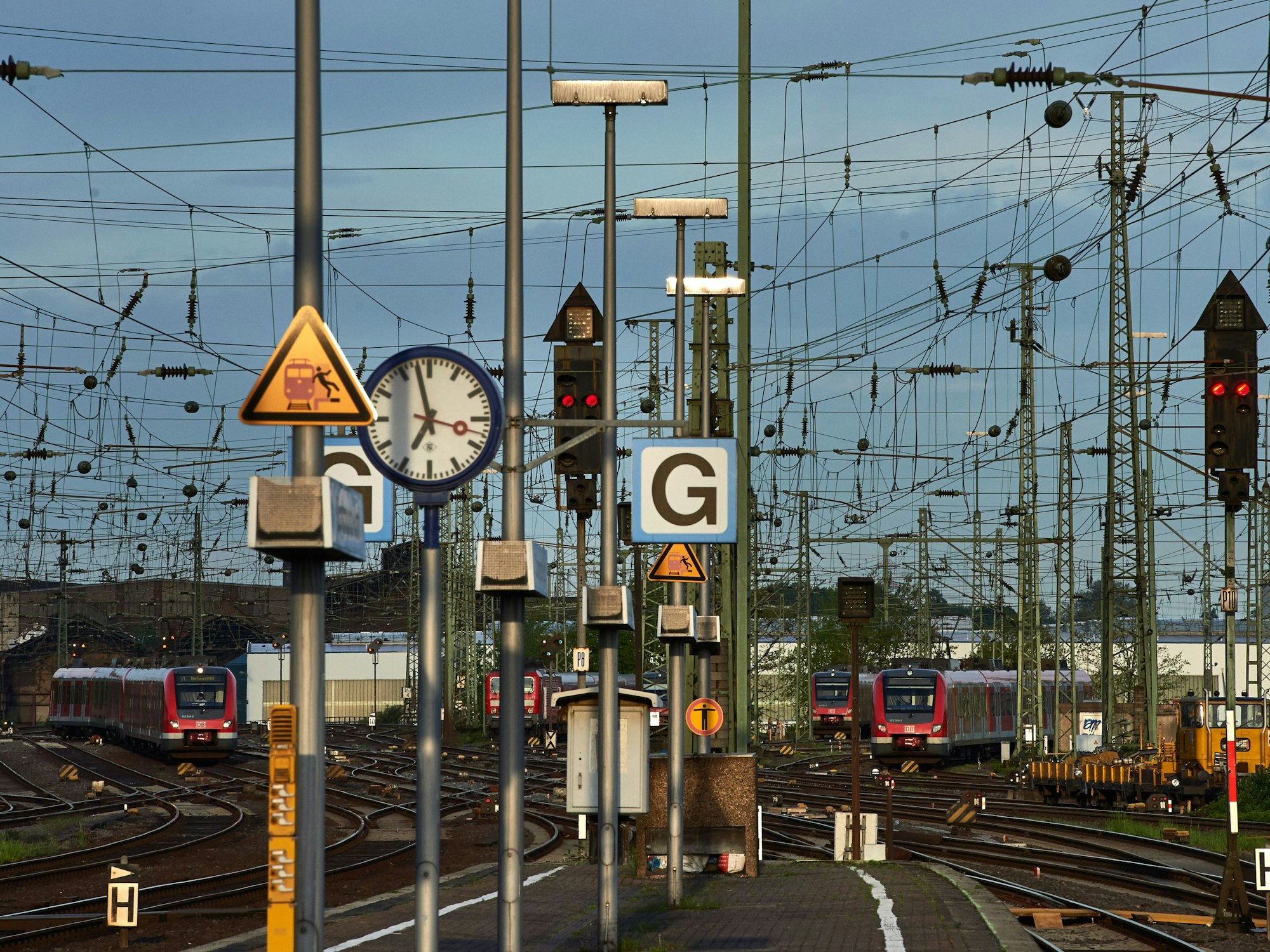 Regionalzüge stehen im Hauptbahnhof in Dortmund auf Abstellgleisen. Zu sehen sind unter anderem auch Oberleitungen und Warnschilder, die vor dem Betreten der Bahnanlage warnen.