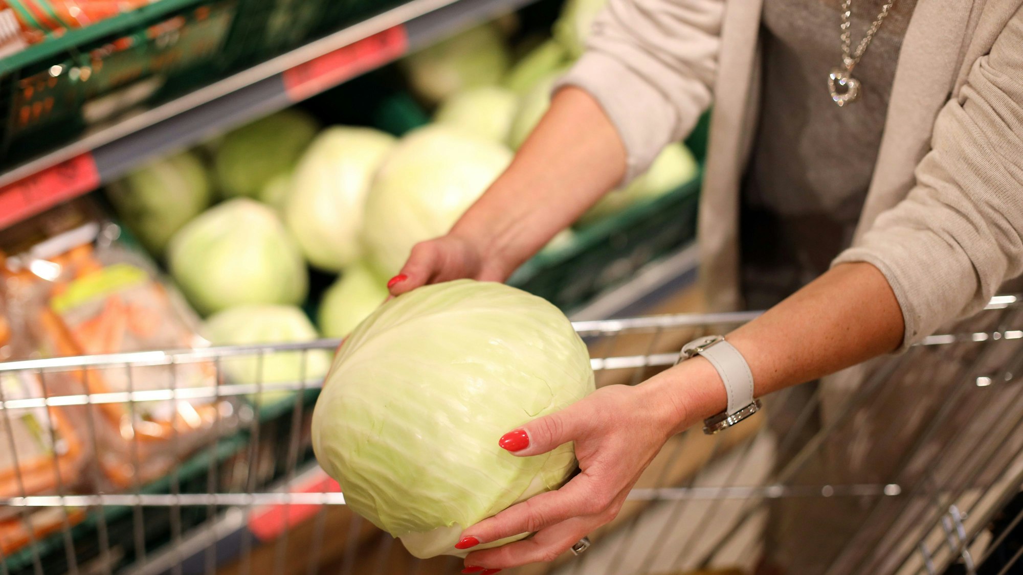 Eine Kundin legt in einer Filiale einer Handelskette Kohl in ihren Einkaufskorb.