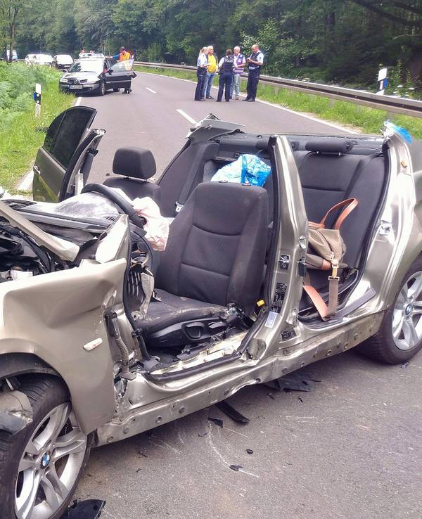 Zwei vollkommen zerstörte Autos liegen nach einem Unfall am Rand der Landstraße L12 zwischen Roetgen und Simmerath in der Eifel. Vier Personen wurden bei dem Zusammenstoß schwer verletzt, davon starb ein Kind später im Krankenhaus.