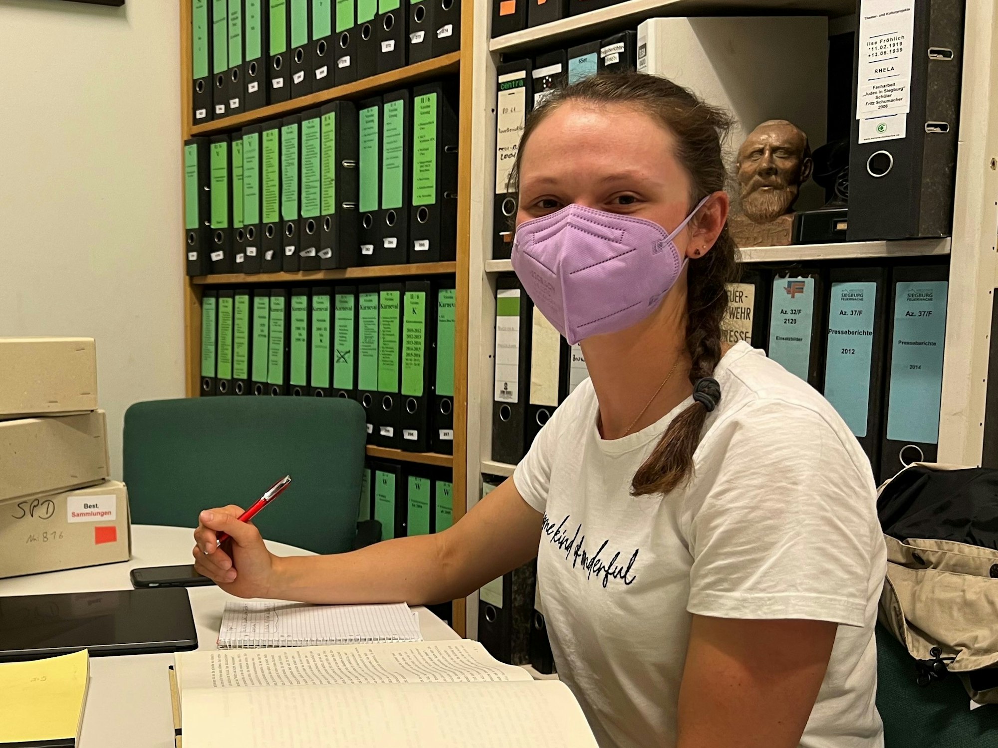 Die Siegburger Ruderin Charlotte Körner sitzt im Siegburger Stadtarchiv vor einem aufgeschlagenen Heft.