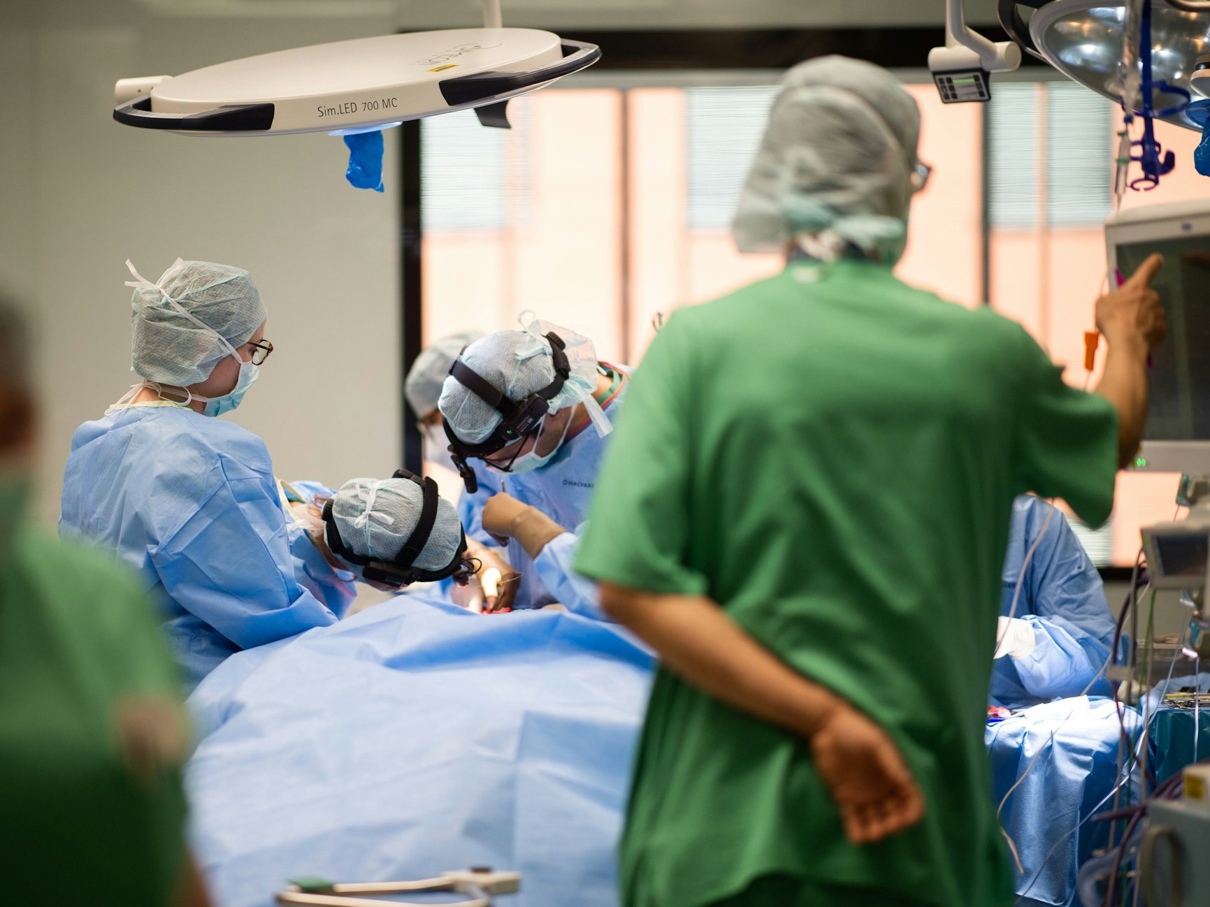 Ein Team aus Ärzten und OP-Helfern steht in einem Operationssaal während einer Operation um einen Patienten.