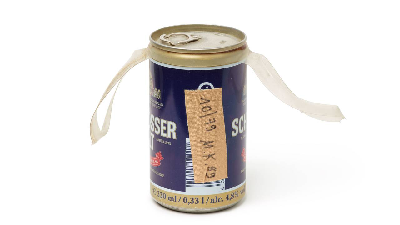 Auf einer Bierdose aus der Brauerei Schlösser klebt ein Pflaster mit der Aufschrift „10/79 M.K. 89“.