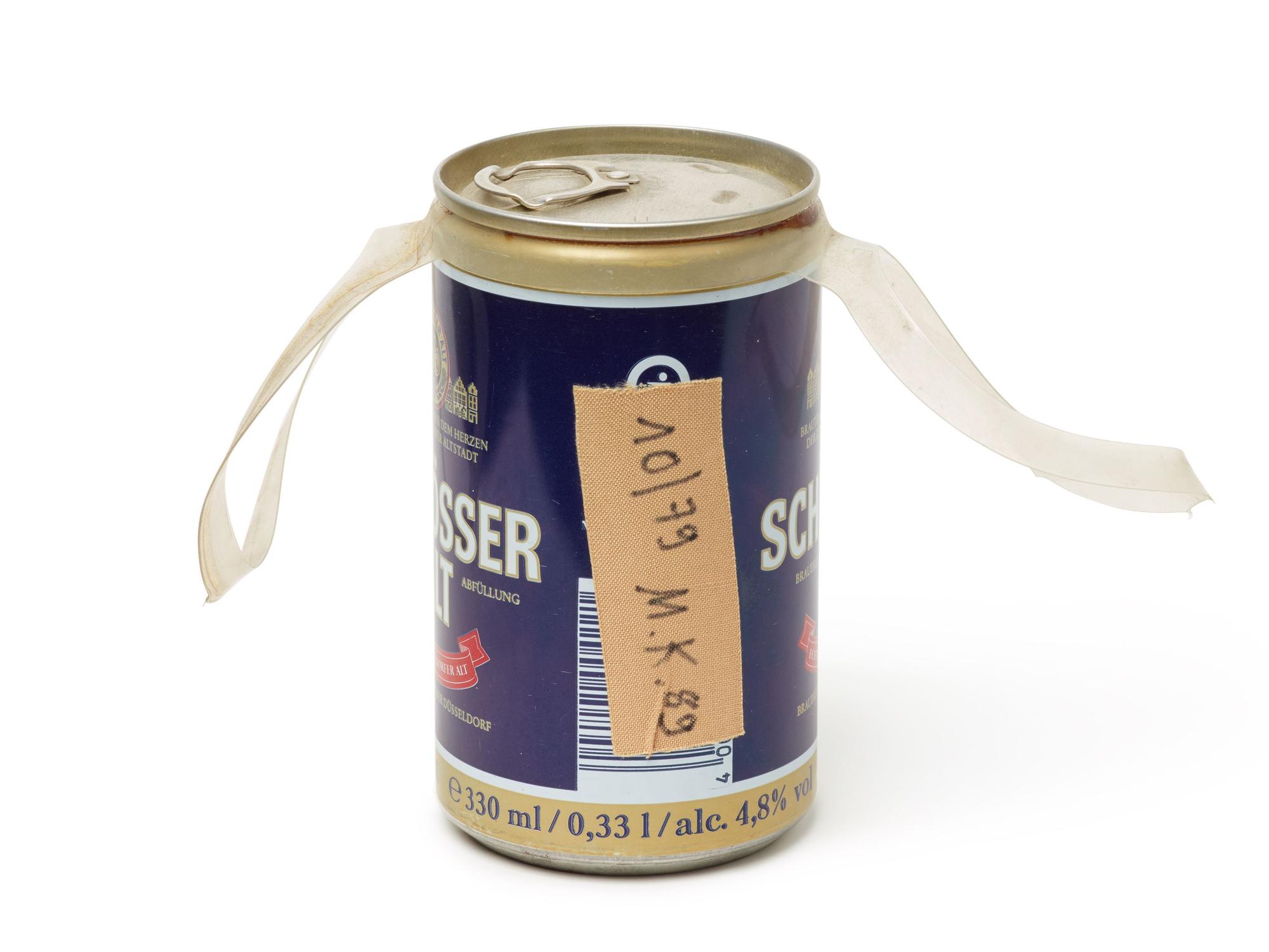 Auf einer Bierdose aus der Brauerei Schlösser klebt ein Pflaster mit der Aufschrift „10/79 M.K. 89“.