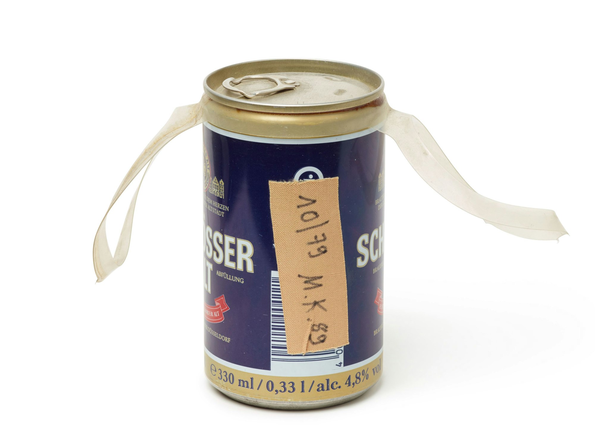 Auf einer Bierdose aus der Brauerei Schlösser klebt ein Pflaster mit der Aufschrift „10/79 M.K. 89“.