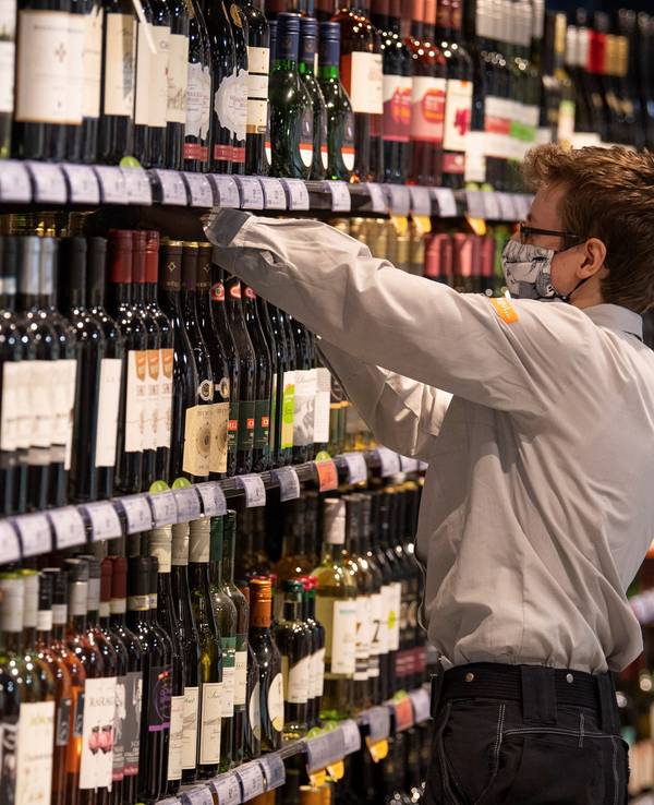 Beim Anblick dieser Flasche im Alkohol-Regal reagieren viele mit Fassungslosigkeit. Unser Foto zeigt einen Supermarkt-Mitarbeiter, der Waren in ein Regal einsortiert.