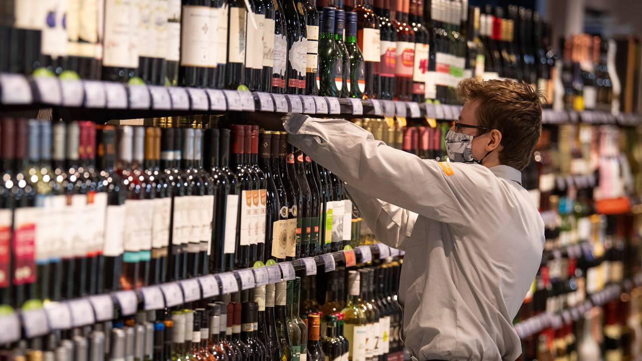 Beim Anblick dieser Flasche im Alkohol-Regal reagieren viele mit Fassungslosigkeit. Unser Foto zeigt einen Supermarkt-Mitarbeiter, der Waren in ein Regal einsortiert.