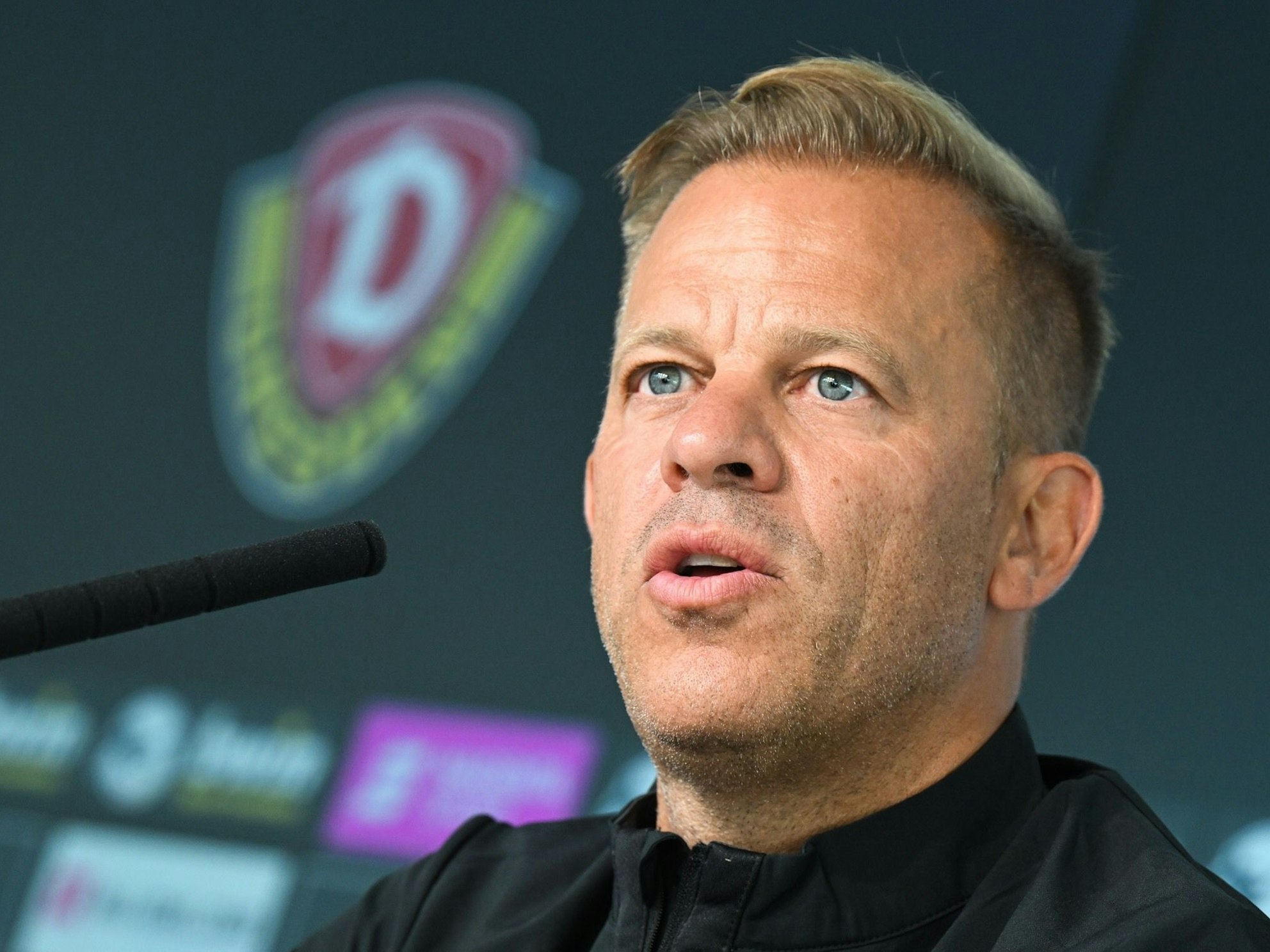 Markus Anfang spricht auf einer Pressekonferenz in ein Mikrofon.