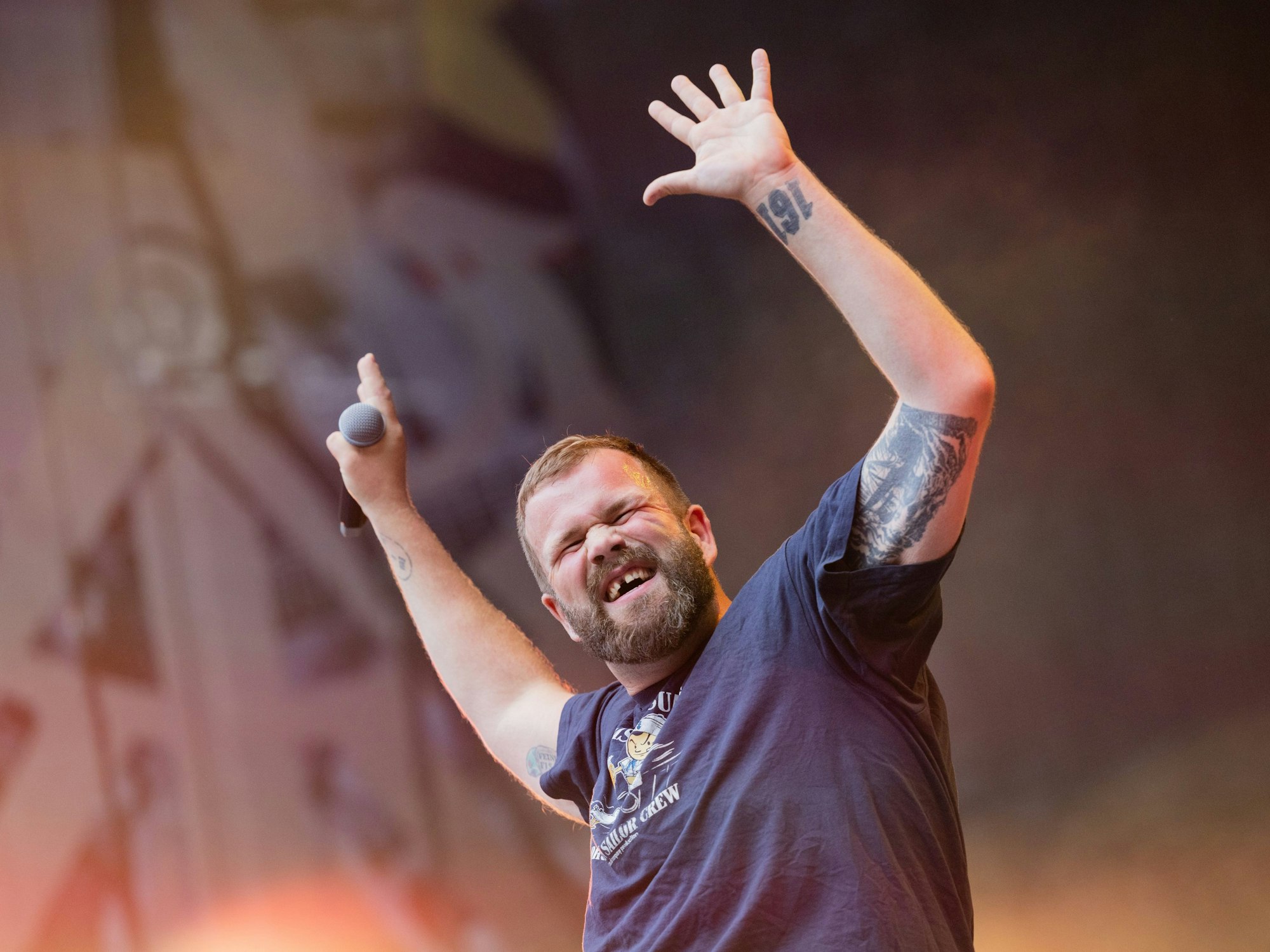 Monchi, Sänger von Feine Sahne Fischfilet, gestikuliert auf der Bühne des Rhein-Energie-Stadions.