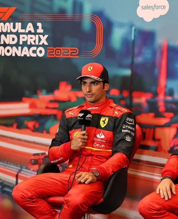Carlos Sainz hält auf einer Pressekonferenz das Mikrofon in der Hand und spricht mit den Journalisten, daneben sein Teamkollege Charles Leclerc.