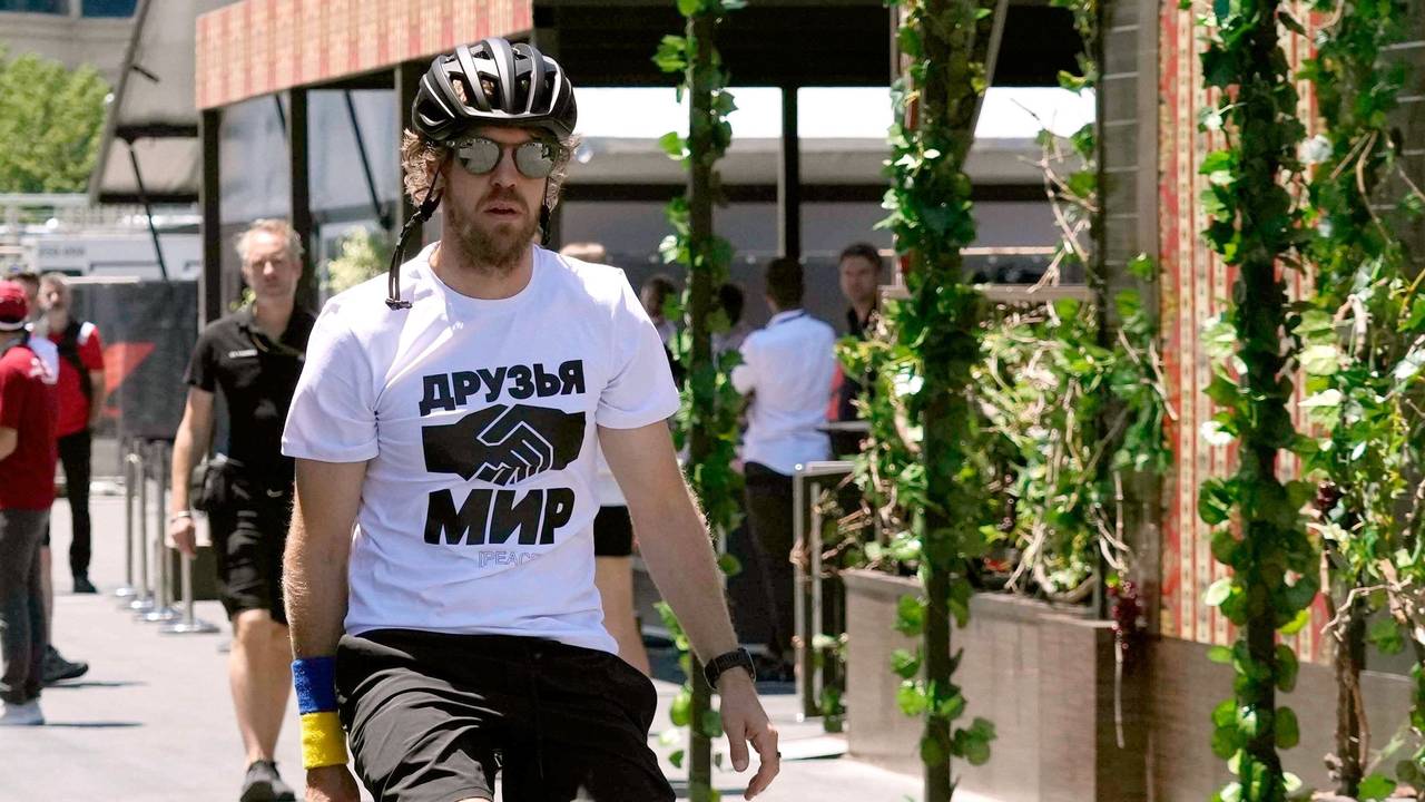 Sebastian Vettel, vom Team Aston Martin, kommt auf einem Fahrrad zum dritten freien Training. Er trägt ein weißes T-Shirt, auf dem die russischen Worte „Freunde“ und „Frieden“ stehen und zwei Hände beim Handschlag abgebildet sind.
