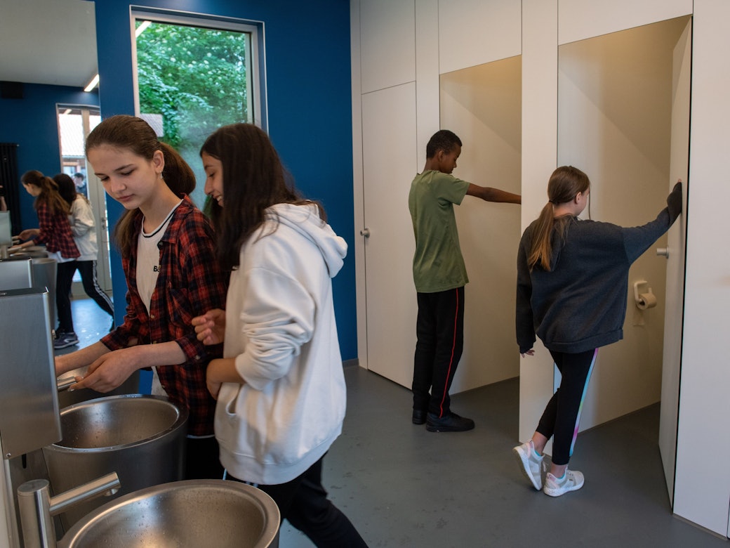 Jungen und Mädchen gehen in eine sogenannte Unisex-Toilette an der Sägefeldschule im Ortsteil Wiblingen (Baden-Württemberg).
