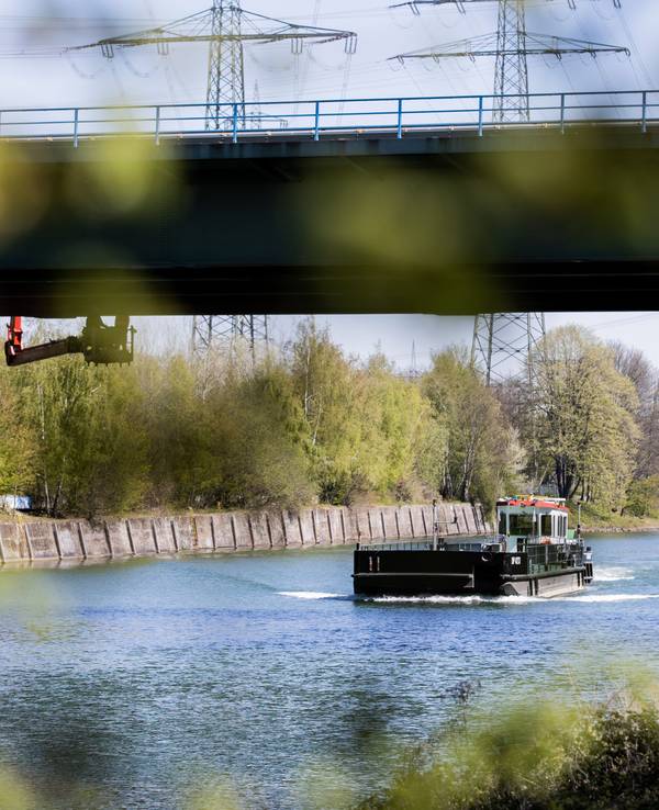 Ein Schiff fährt auf dem Rhein-Herne-Kanal unter einer Brücke hindurch.