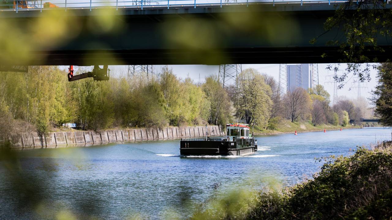 Ein Schiff fährt auf dem Rhein-Herne-Kanal unter einer Brücke hindurch.