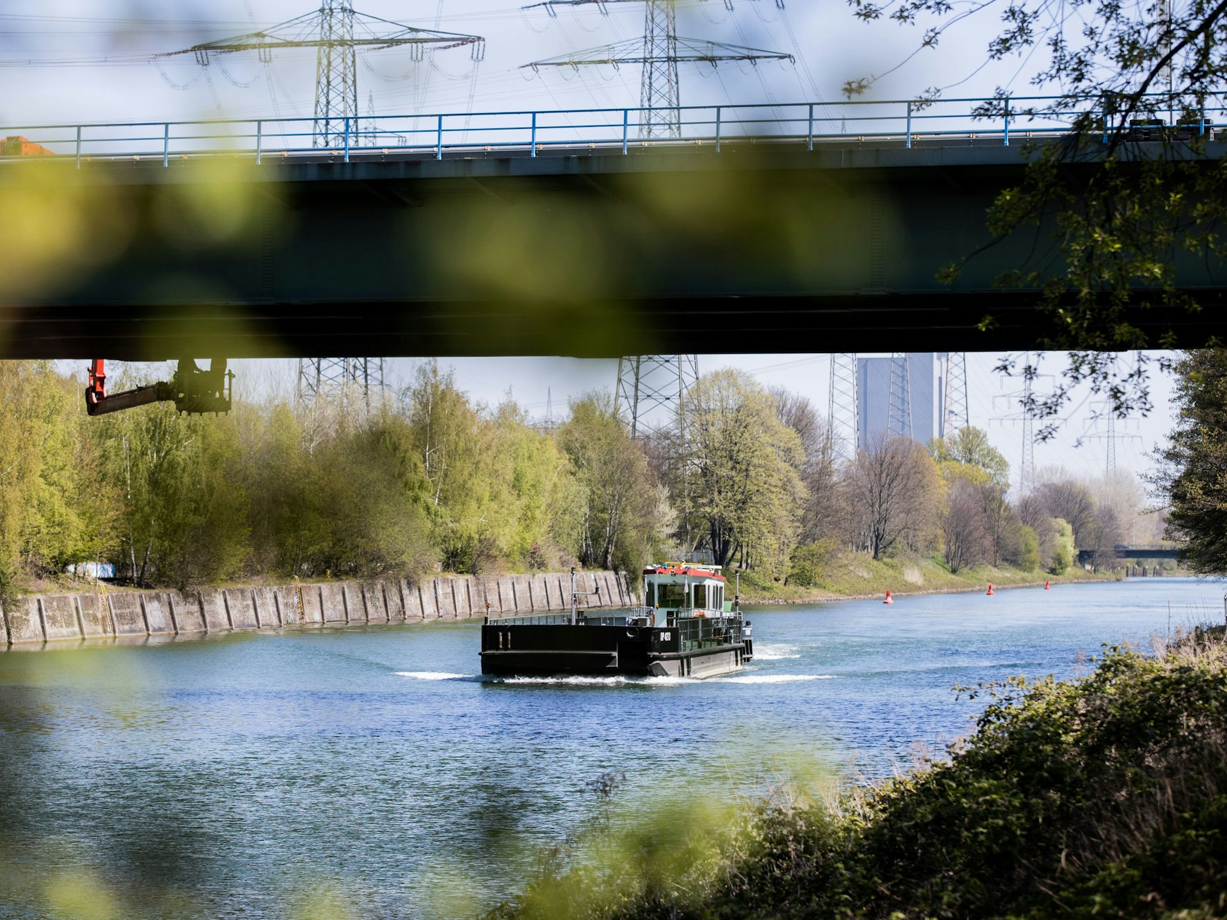 Ein Schiff fährt auf dem Rhein-Herne-Kanal unter einer Brücke hindurch.