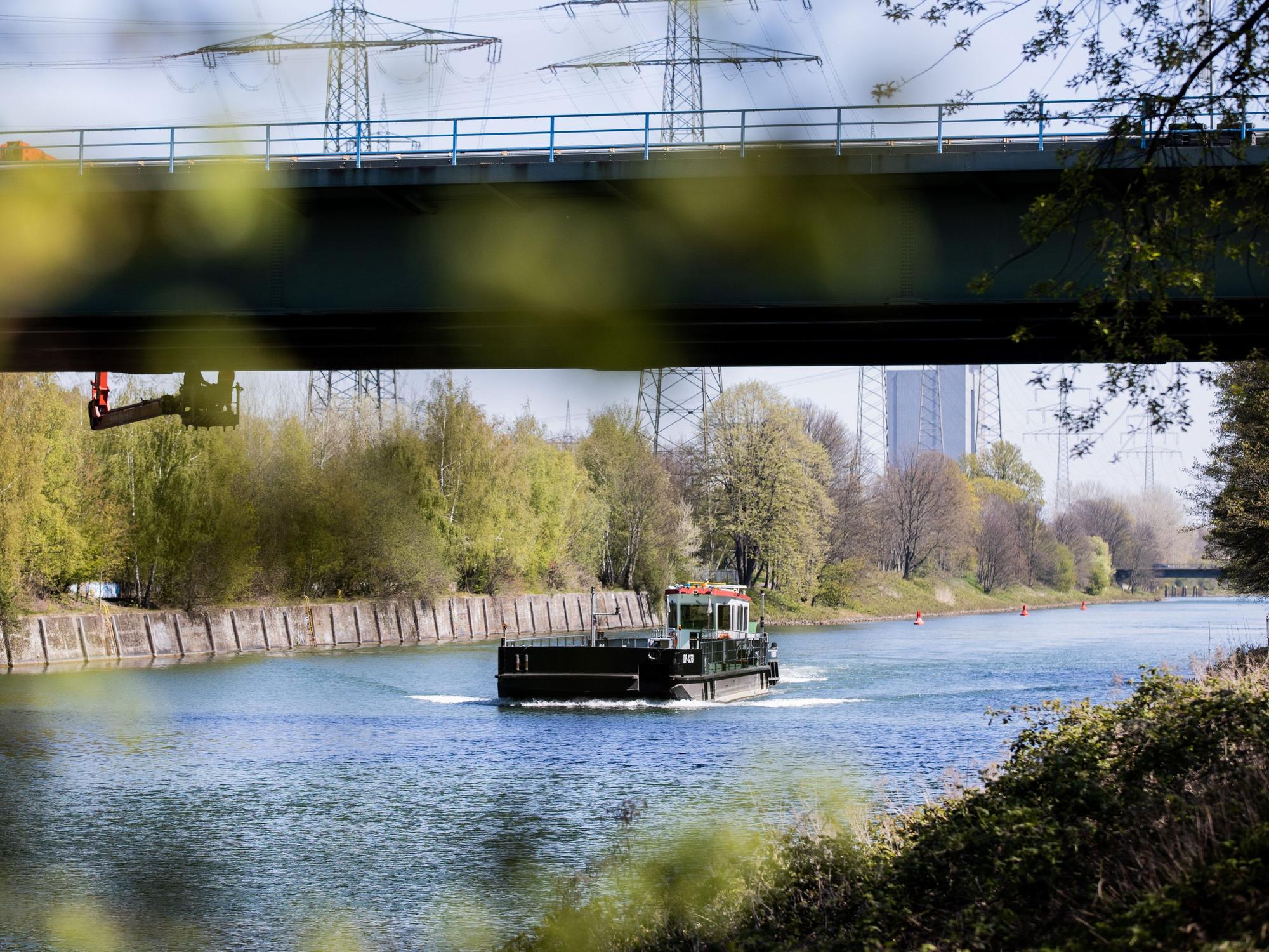 Ein Schiff fährt auf dem Rhein-Herne-Kanal unter einer Brücke hindurch.
