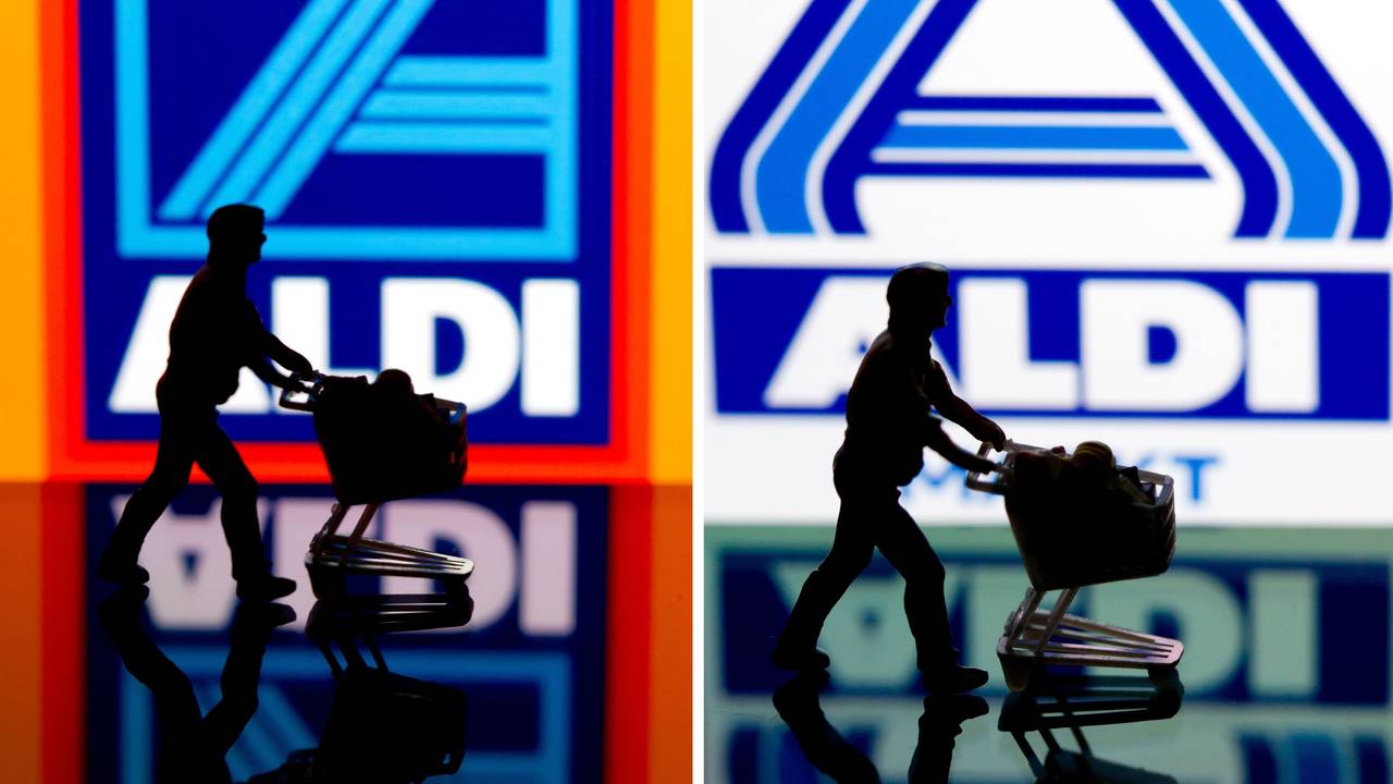 Eine kleine Plastikfigur mit einem Einkaufswagen in Berlin vor einem Logo von Aldi Süd (links) und Aldi Nord