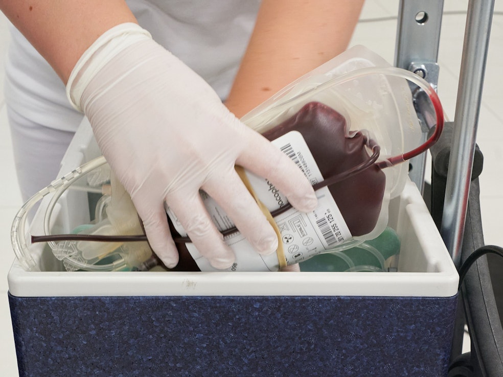 Ein Mitarbeiter des DRK-Blutspendedienstes verstaut eine Blutkonserve in einem Kühlbehälter.