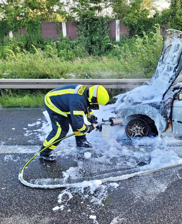 Ein Feuerwehrmann besprüht den Unfallwagen mit Löschschaum.