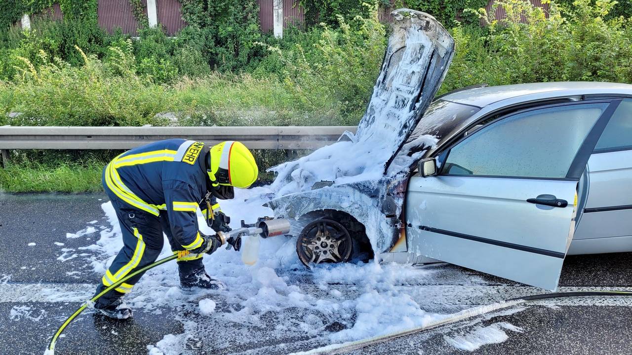 Ein Feuerwehrmann besprüht den Unfallwagen mit Löschschaum.