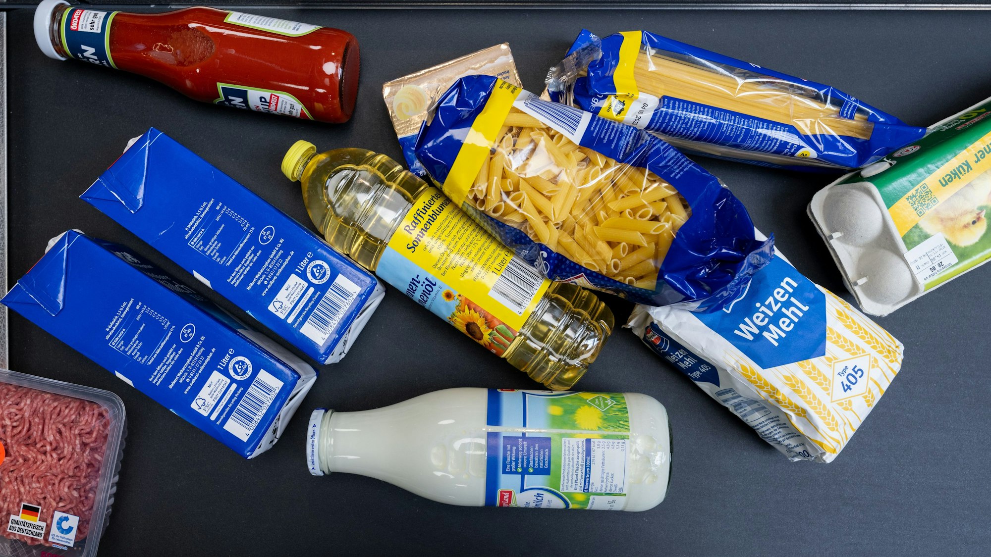 Lebensmittel, darunter Sonnenblumenöl und Getreideprodukte, liegen in einem Supermarkt an der Kasse auf dem Band.
