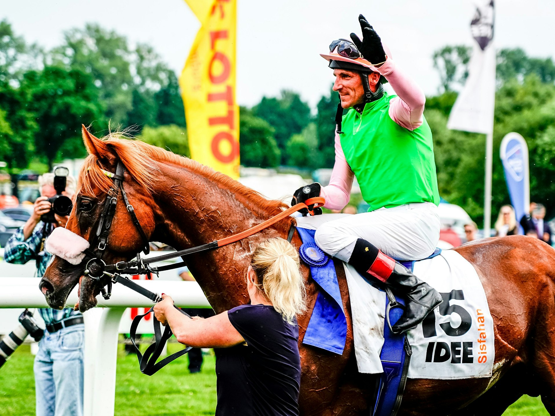 Jockey Andrasch Starke sitzt auf seinem Pferd und winkt.