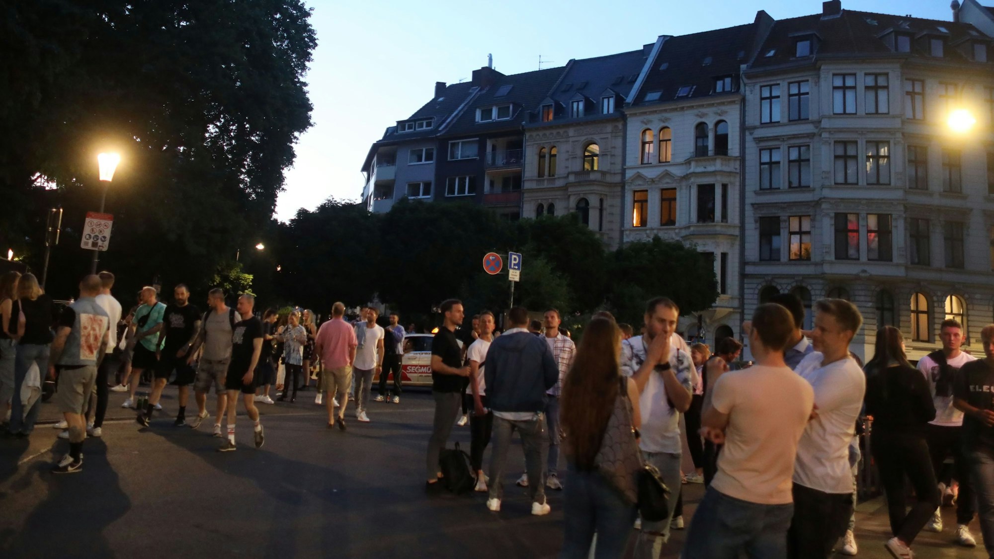 Menschen treffen sich auf einem Platz, stehen in Gruppen beisammen.