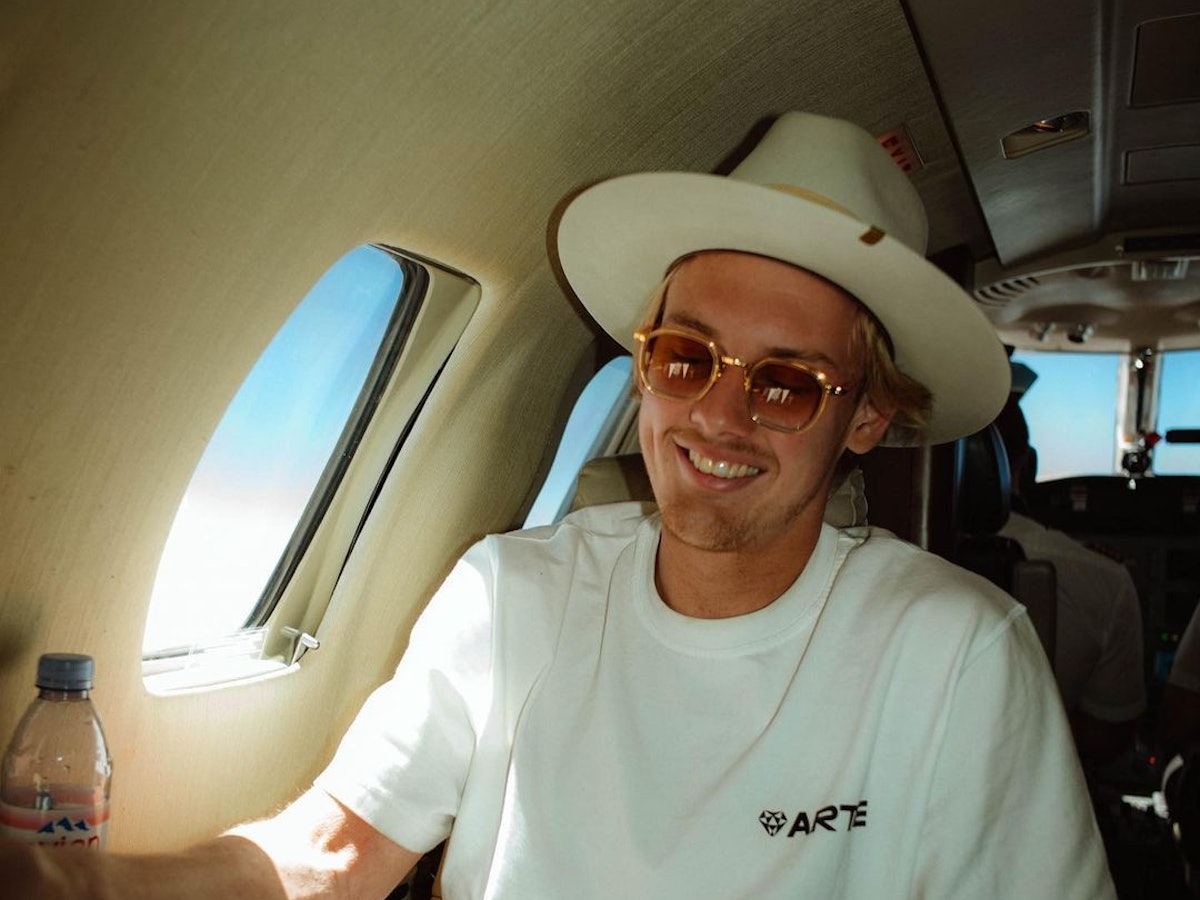 Julian Brandt sitzt mit Hut in einem Privatjet.