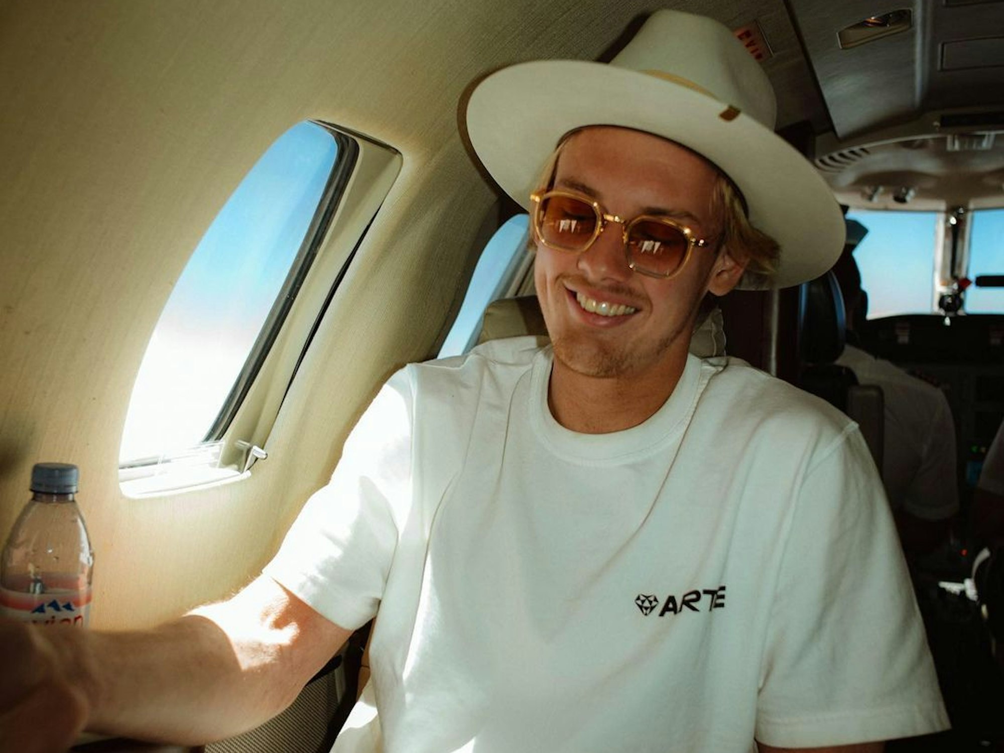 Julian Brandt sitzt mit Hut in einem Privatjet.