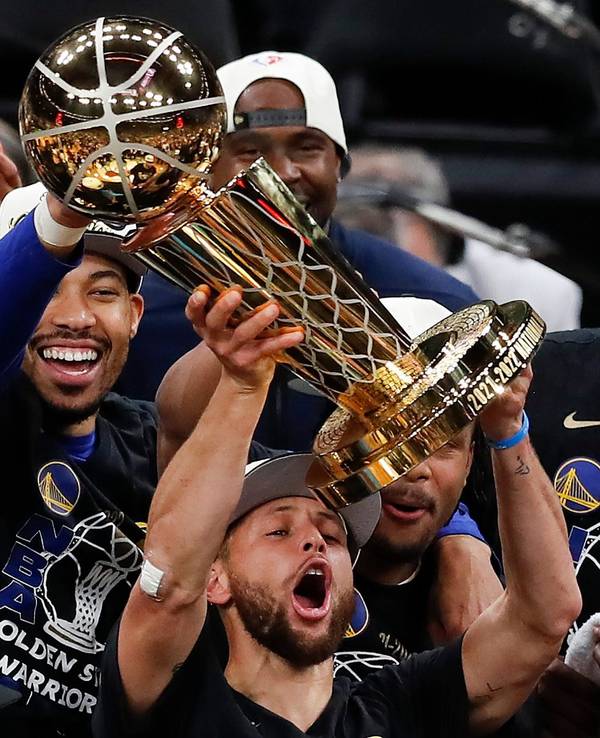 Stephen Curry stemmt vor seinen feiernden Kollegen die NBA-Trophäe in die Luft.