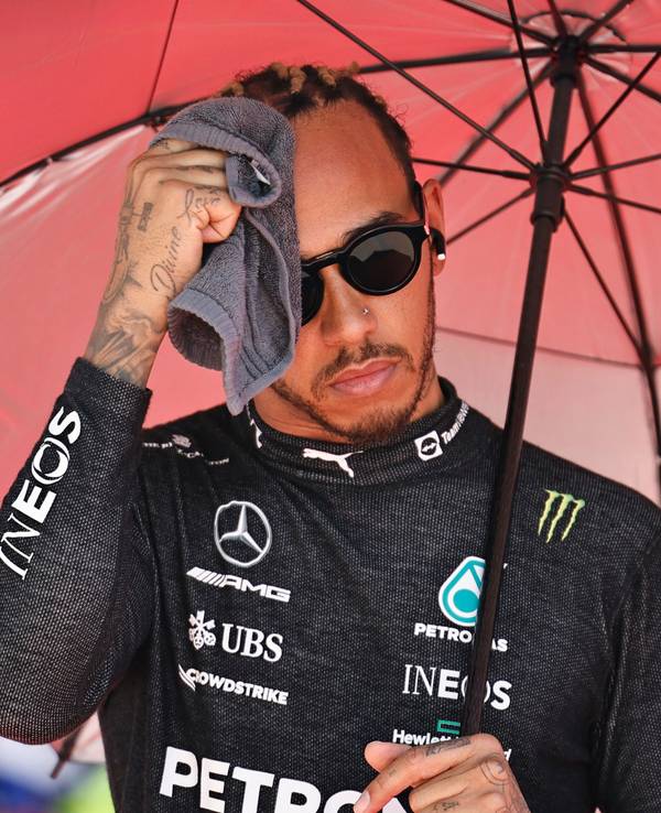 Lewis Hamilton aus Großbritannien vom Team Mercedes wischt sich vor dem Rennen unter einem Sonnenschirm den Schweiß mit einem Handtuch vom Gesicht.