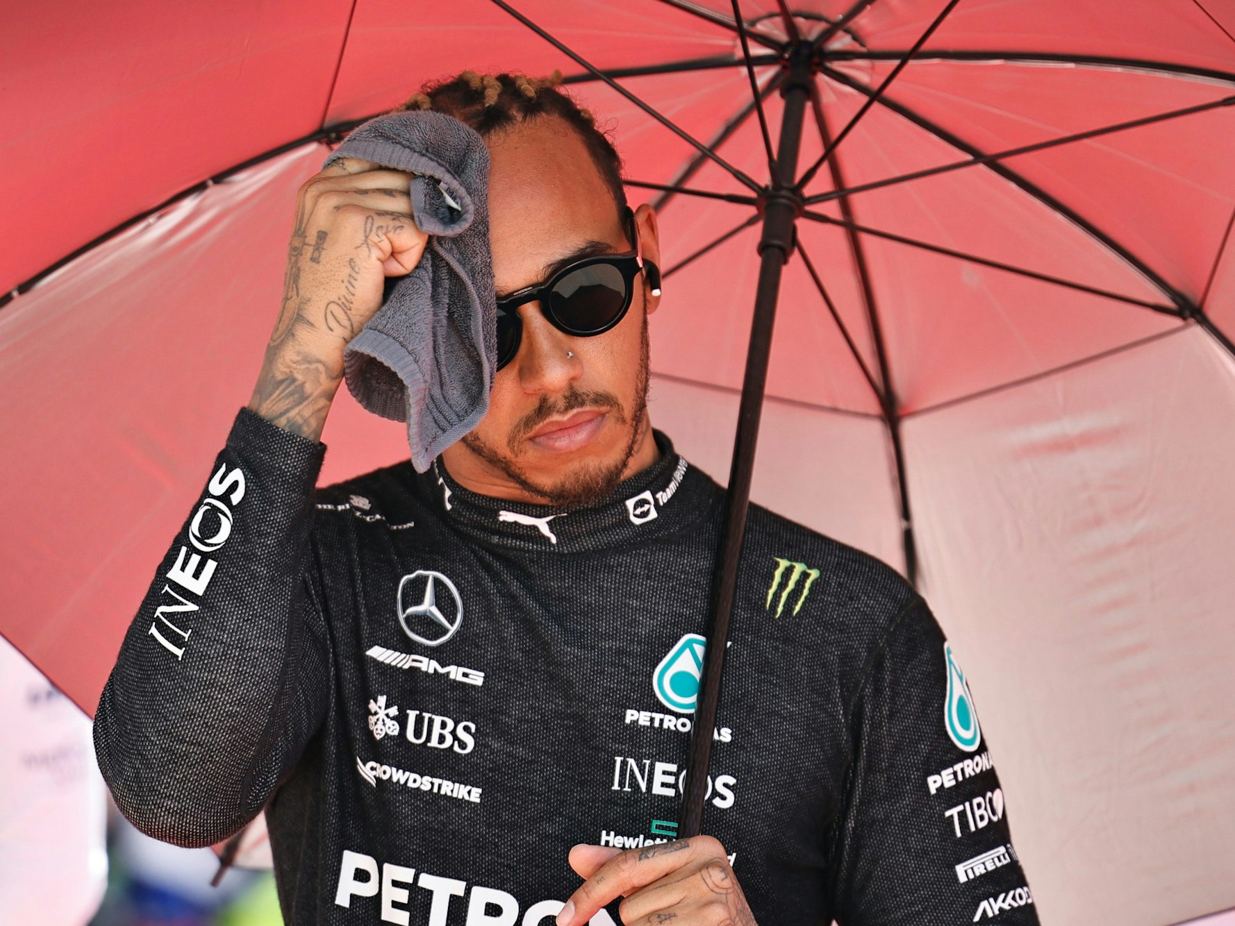 Lewis Hamilton aus Großbritannien vom Team Mercedes wischt sich vor dem Rennen unter einem Sonnenschirm den Schweiß mit einem Handtuch vom Gesicht.