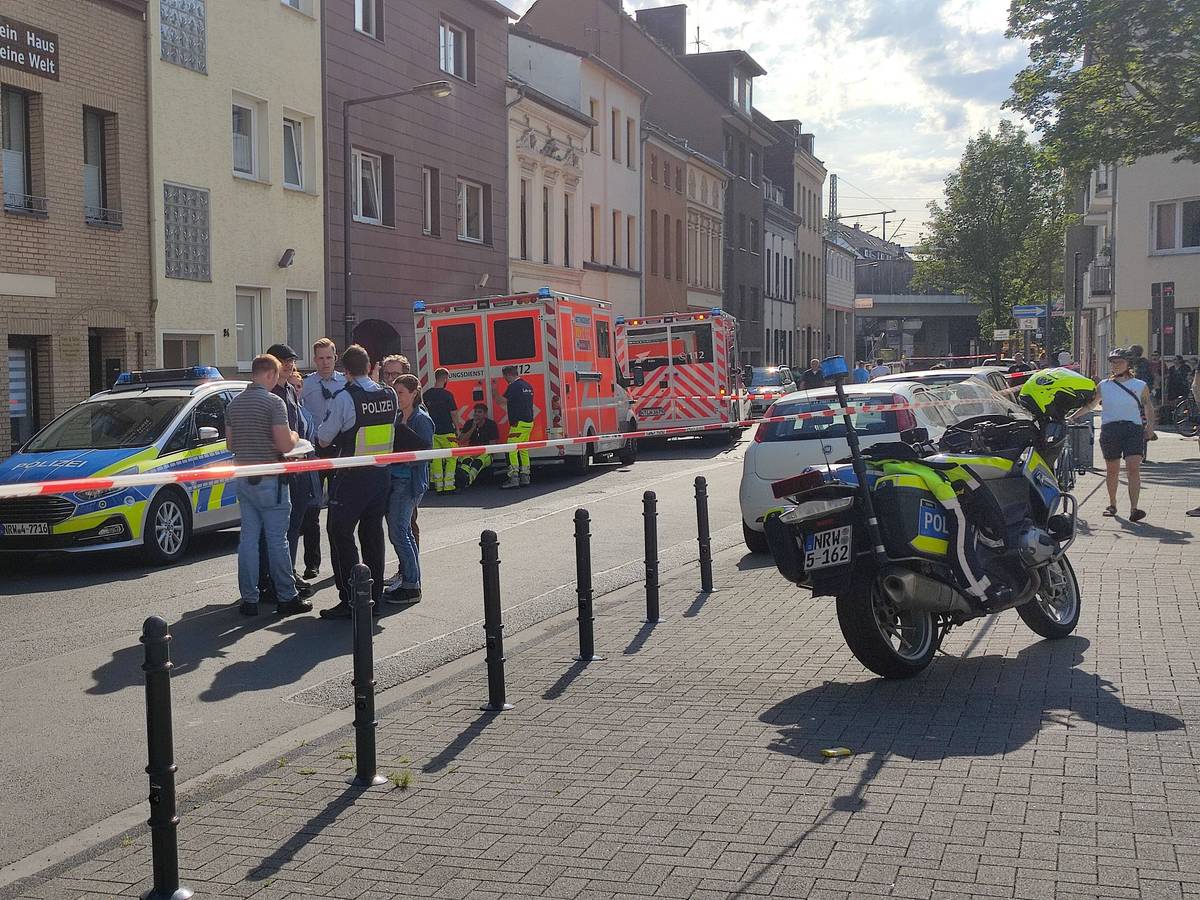Einsatzkräfte der Polizei sowie ein Streifenwagen und mehrere Fahrzeuge des Rettungsdienstes stehen vor dem Haus, in dem das Tötungsdelikt passierte.