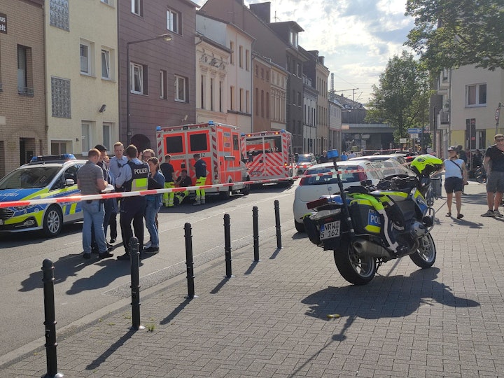 Einsatzkräfte der Polizei sowie ein Streifenwagen und mehrere Fahrzeuge des Rettungsdienstes stehen vor dem Haus, in dem das Tötungsdelikt passierte.