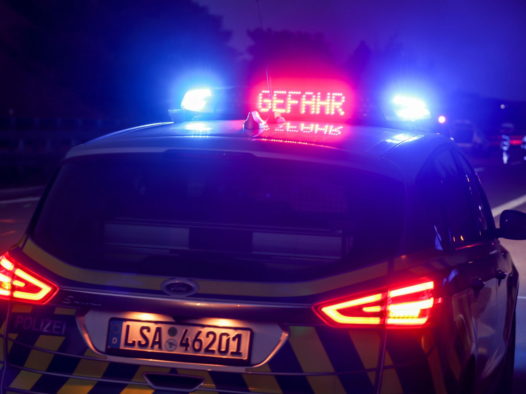 Mit Blaulicht und der Anzeige „Gefahr“ steht ein Polizeifahrzeug auf der Autobahn 14 bei Halle-Trotha, die Aufnahme dient als Symbolfoto.