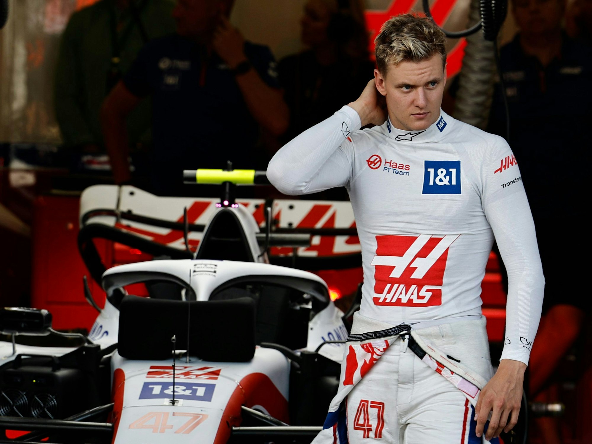 Mick Schumacher steht vor seinem Auto und fasst sich in den Nacken.