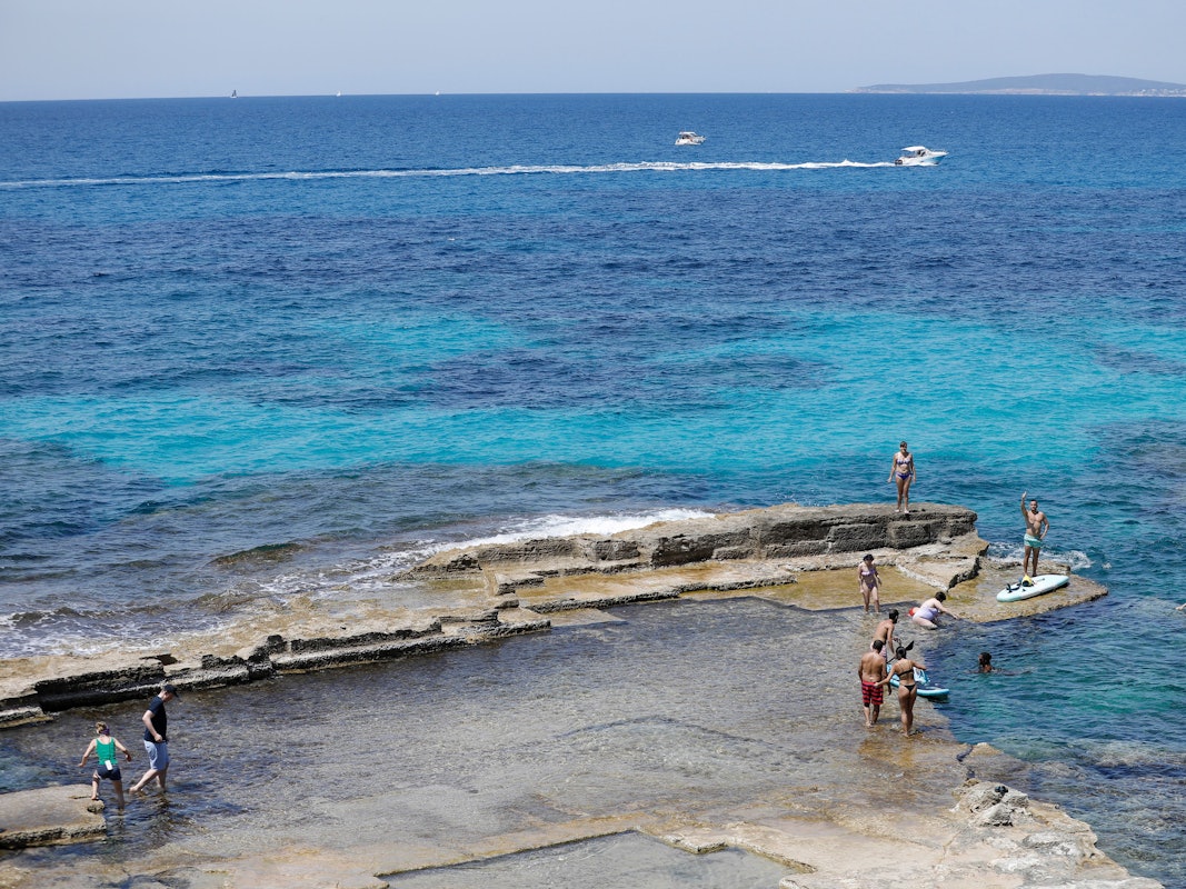 Menschen entspannen sich am Felsenstrand von Maioris an der Südostküste Mallorcas.