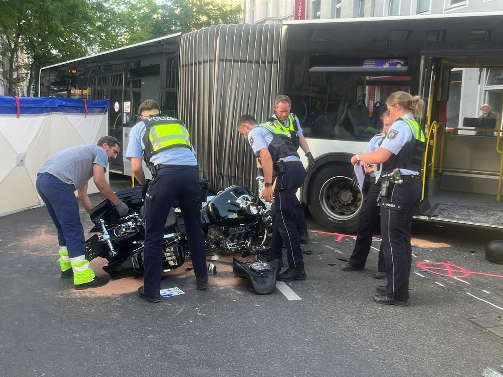 Einsatzkräfte der Polizei am Unfallort in Köln-Nippes. Dort kollidierte ein Motorradfahrer mit einem KVB-Bus.