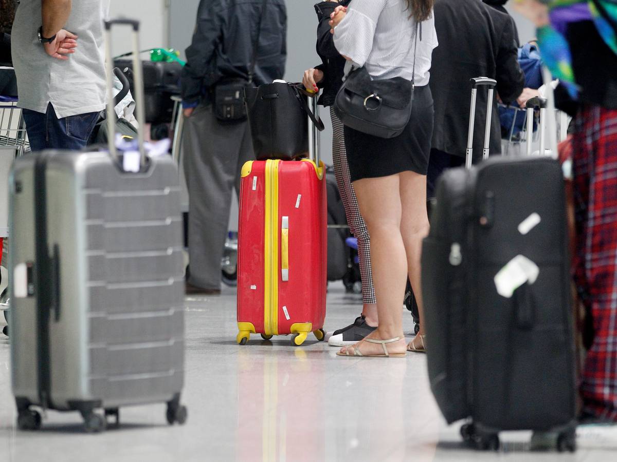 Fluggäste warten am Düsseldorfer Flughafen vor einem Check-In-Schalter auf ihre Abfertigung.