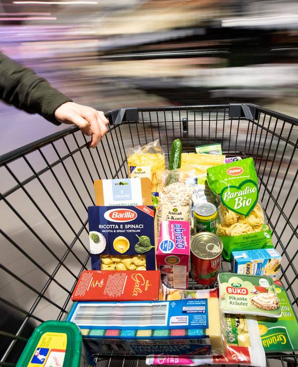 Ein Einkaufswagen wird durch einen Supermarkt geschoben.