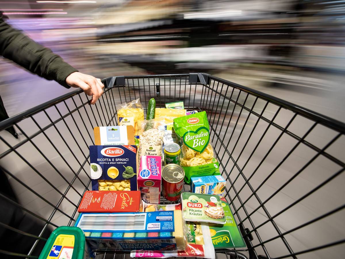 Ein Einkaufswagen wird durch einen Supermarkt geschoben.