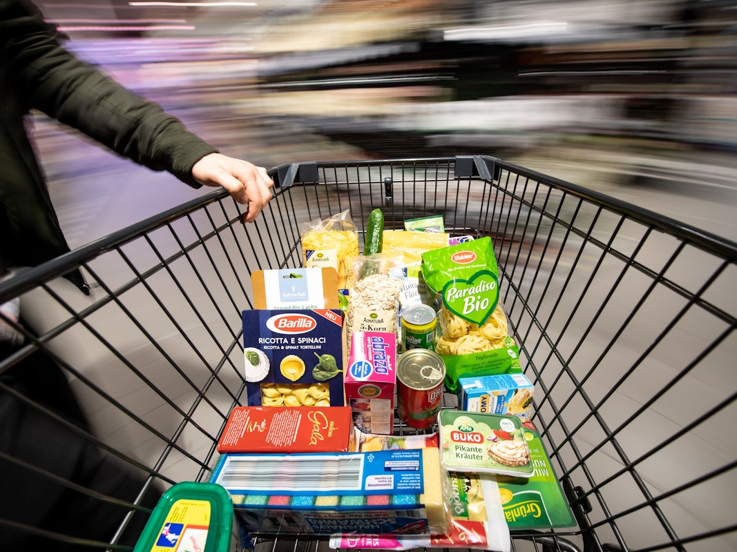 Ein Einkaufswagen wird durch einen Supermarkt geschoben.